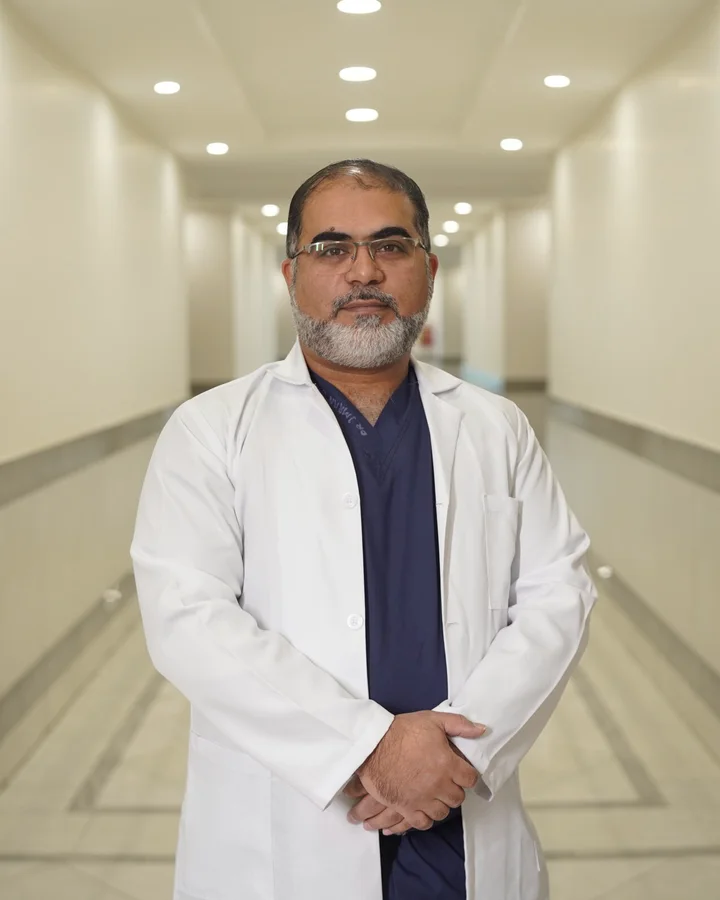 Dr Imran Salim Malik in a white coat in a hospital corridor